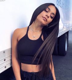 a woman with long hair leaning against the side of a white truck and looking off into the distance