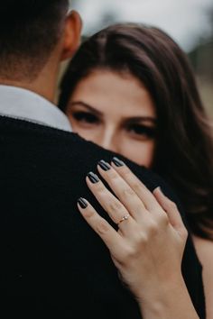 a man and woman embracing each other with their hands on the back of his shoulder