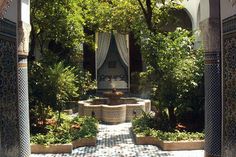 an outdoor fountain surrounded by greenery and stonework in the middle of a courtyard