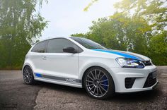 a white car with blue stripes parked in front of some trees