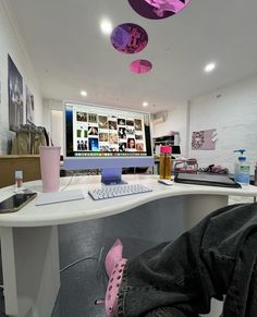 a desk with a keyboard, mouse and pink shoes hanging from it's ceiling