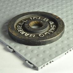 an old metal object sitting on top of a white surface with holes in the middle