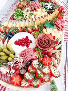 a platter filled with meats, cheeses and fruit on top of a wooden table