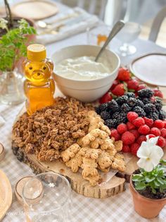 a table topped with plates and bowls filled with food next to wine glasses, utensils and flowers