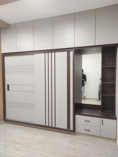 an empty room with white cupboards and drawers on the wall, two people are in the mirror