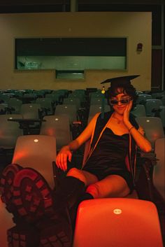 a woman sitting in an auditorium with her hand on her face and looking at the camera