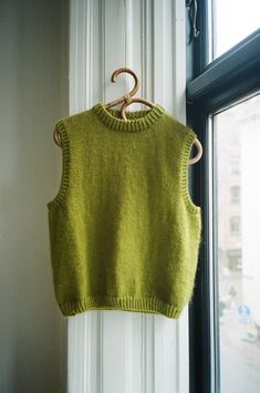 a green sweater hanging on a window sill