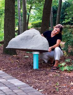 a woman kneeling down next to a large rock