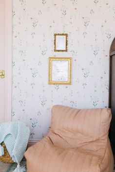 a room with floral wallpaper and a futon in front of the door is shown