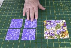 someone is cutting out small square pieces on a green mat with purple and yellow flowers