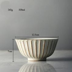 a white bowl sitting on top of a table next to a measuring tape and cup