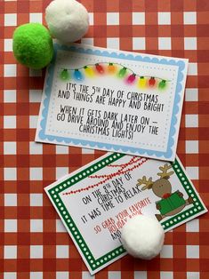 two christmas cards on top of a table next to a green and white pom - pom