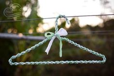 a close up of a green string with a white bow on it and some trees in the background