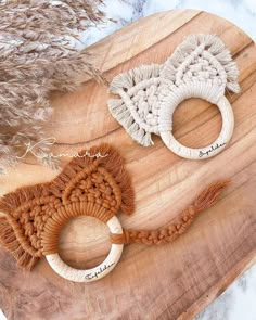 two pieces of yarn are sitting on a wooden board next to some dried plants and feathers