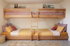 two bunk beds in a bedroom with yellow and pink pillows on the bottom bunk bed