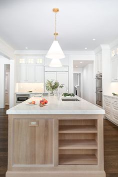 a kitchen with white cabinets and an island in the middle is lit by a pendant light