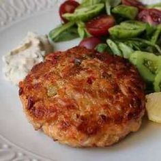 a close up of a plate of food with salad and meat patties on it