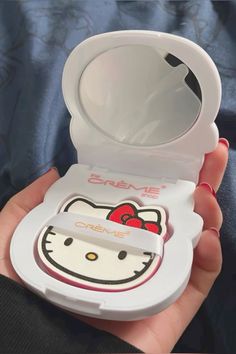 someone is holding a hello kitty compact mirror in their hand