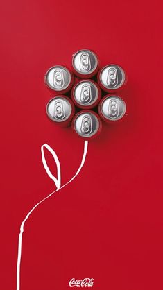 six cans of coca - cola are arranged in the shape of a flower on a red background