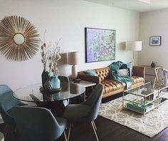 a living room filled with furniture and a glass table surrounded by blue chairs, rugs and lamps