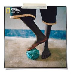 a person standing on top of a blue ball in the middle of a cement floor