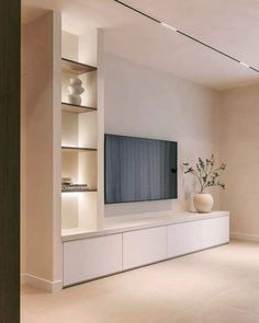 a living room with white furniture and a flat screen tv mounted to the side of a wall