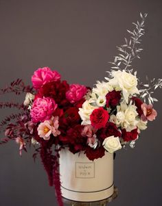 a white bucket filled with lots of red and white flowers