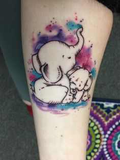 an elephant and her baby are sitting on the ground in front of a colorful background