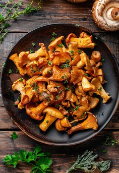 mushrooms and parsley in a black plate on a wooden table