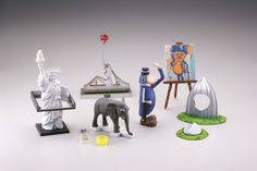 an assortment of miniature statues and art work on display in front of a white background