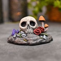 there is a skull sitting on top of a rock with a rose in its mouth