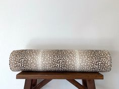 a pillow sitting on top of a wooden bench in front of a white wall and floor