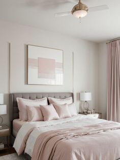 a bed with pink sheets and pillows in a bedroom next to a painting on the wall