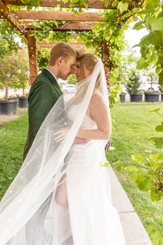 a bride and groom pose under the pergolia at their wedding