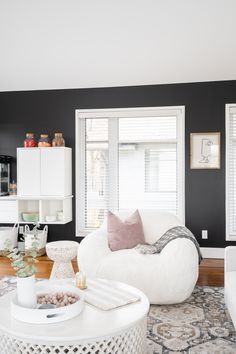 a living room with black walls and white furniture on the floor, including a round coffee table