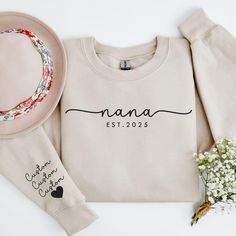 Make Nana feel extra special with our Personalized Nana Sweatshirt! This cozy sweater features the "Est." year and her grandkids' names on the sleeves, making it the perfect Mother's Day or birthday gift. Whether she goes by Nana, Nini, Nonna, or Nene, this custom sweatshirt is a thoughtful way to celebrate her love for her grandchildren. Ideal for new grandmothers or seasoned ones, it's a heartfelt and unique gift she'll cherish forever. Perfect for any occasion, this Nana gift is a sweet remin Nana Sweatshirt Ideas, Nana Sweatshirt, Love For Her, Nana Gifts, Mama Sweatshirt, Mothersday Gifts, Custom Sweatshirts, Cozy Sweater, Grandchildren