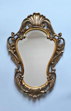 an ornate gold framed mirror against a blue wall