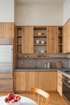 a kitchen with wooden cabinets and stainless steel appliances, along with a bowl of fruit on the table