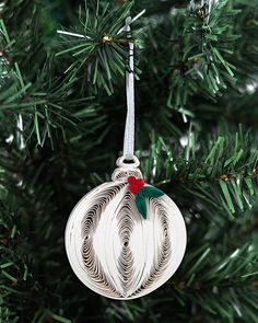 a white ornament hanging from a christmas tree with red and green decorations on it