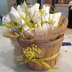 a basket filled with white and yellow flowers on top of a table covered in burlocks