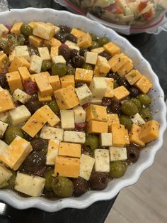 a bowl filled with cheese and olives on top of a table next to other dishes