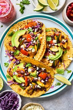 three tortillas with black beans, avocado and red cabbage on a plate