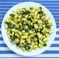 a white plate topped with zucchini and other veggies on top of a blue table cloth