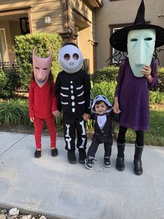 three children in halloween costumes standing on the sidewalk