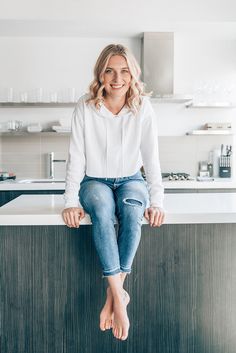 a woman sitting on top of a counter in a kitchen