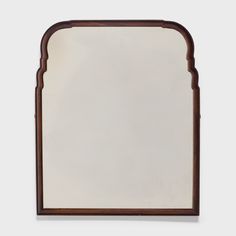 a mirror with an arched wooden frame on the front and back sides, hanging on a wall