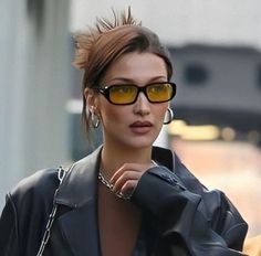 a woman wearing yellow sunglasses is walking down the street