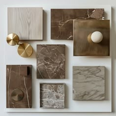 several different types of marble tiles on a white wall with gold accents and knobs