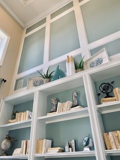 shelves with books and vases on them in a room that is painted light blue