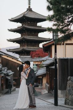 a man and woman standing in front of a tall building with pagodas on it